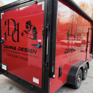 Red Danna Design trailer with black logo, welding graphic, and contact info showcasing Mobile Welding Service in Sumter SC for all your fabrication and welding needs.